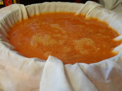 filtering rose hip liquid through cheese cloth